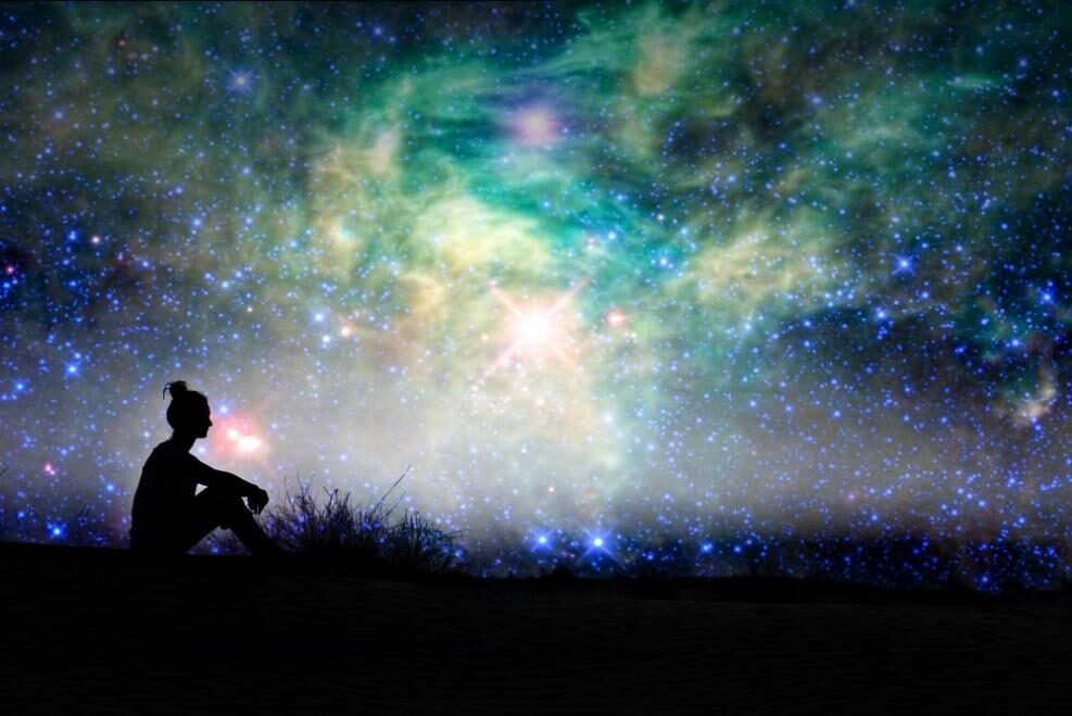 Silhouette gazing at a colorful galaxy filled with stars on a starry night.