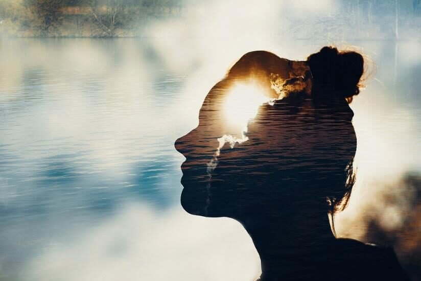 Silhouette of a person with sunlight reflecting on tranquil water.